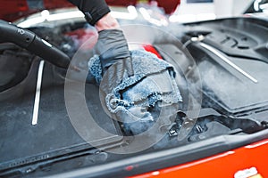 closeup shot of cleaning car engine with a microfiber cloth and steam