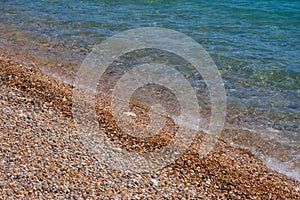 Closeup shot of the coastline with clear water and pebbles