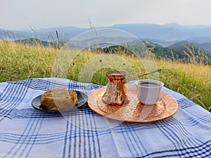 Closeup shot of a coffee and a sweet treat on a picnic set up with the beautiful view background
