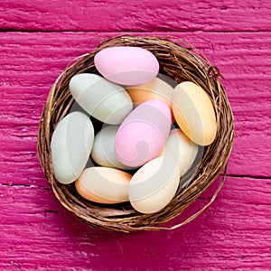 Closeup shot of colored Easter eggs in a woven basket on a purple surface
