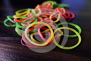 Closeup shot of colorful rubber bands isolated on brown wooden table