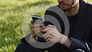 Closeup shot of concentrated young businessman texting his girlfriend waiting in park. Man chatting social media using