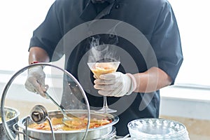 Closeup shot of the cook putting a shrimp dish into a cocktail glass