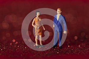Closeup shot of a couple of figurines standing on red glitter background