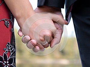 Closeup shot of a couple holding hands with an engagement ring - love concept