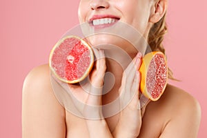 Close up shot cropped blonde half naked woman 20s perfect skin nude make up hold in hand grapefruit isolated on pastel