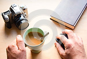 Closeup shot of a cup of tee and a camera on a wooden table