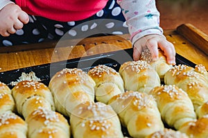 Closeup shot of the cute hand of a baby grabbing one of the freshly baked small croissants