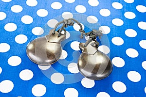 Closeup shot of dark brown castanets laying on a blue polka-dotted surface