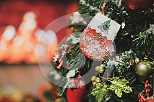 Closeup shot of decorated sock hanging on pine branch of Christmas tree with a ball and various decor xmas ornaments cover with