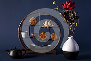 Closeup shot of a decorative shelf with cups, bowls, traditional Chinese mooncakes, and flowers