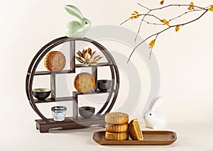 Closeup shot of a decorative shelf with cups, a ceramic rabbit, traditional Chinese mooncakes