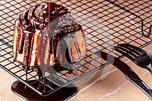 Closeup shot of a delicious cinnamon roll on the oven net tray with drizzles of melted chocolate