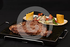 Closeup shot of delicious steak with vegetable sidedish isolated on a black background