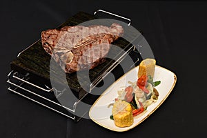 Closeup shot of delicious steak with vegetable sidedish isolated on a black background