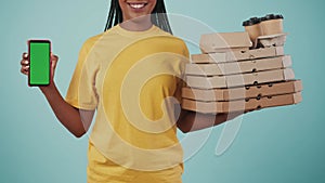 Closeup shot. Delivery woman in uniform holding stack of pizza boxes with coffee and smartphone. Advertising area