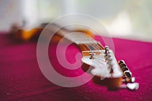 Closeup shot of details on an electric guitar laying on a pink surface