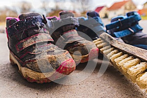 Closeup shot of dirty children's boots and a shoe brush