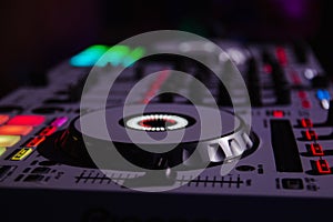 Closeup shot of a DJ turntable with various track controls in a night bar