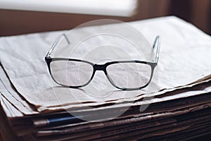 Closeup shot of eyeglasses on the stack of newspapers - learning concept