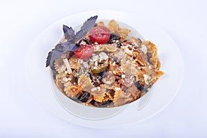 Closeup shot of farfalle pasta with black olives and a slice of tomato on top