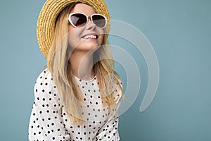 Closeup shot of fascinating smiling positive young blonde woman wearing summer dress straw hat and stylish sunglasses