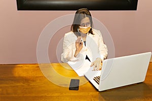 Closeup shot of a female doctor with medical face mask working with laptop at her desk