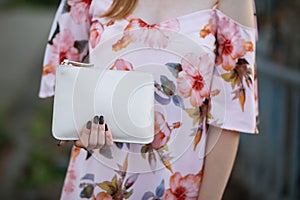 Closeup shot of female hand holding white leather purse. Space f
