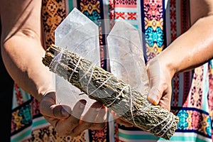 Closeup shot of female hands holding a roll of sage and crystal mineral towers