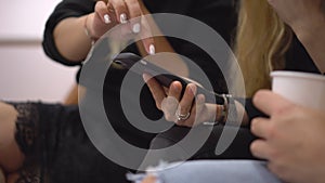 Closeup shot of female hands. Women sit at a conference with phones. Women write down information to themselves in phone