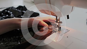 Closeup shot of female hands working on sewing machine. Young woman using a sewing machine at home or in workshop