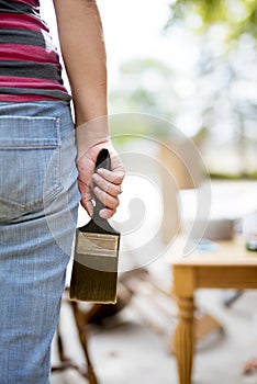 Closeup shot of a female holding a big paintbrush with a blurred background