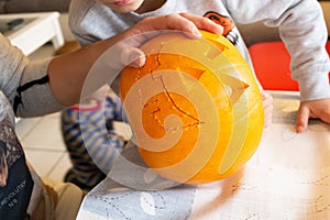 Closeup shot of a female's hand carving a pumpkin head for Halloween