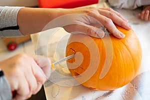 Closeup shot of a female's hand carving a pumpkin head for Halloween