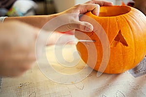 Closeup shot of a female's hand carving a pumpkin head for Halloween