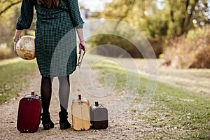 Closeup shot of a female standing on a pathway near her old suitcases while holding the bible