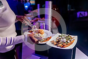 Closeup shot of a female who takes delicious food from a buffet table