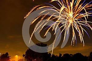 Closeup shot of a firework in golden and blue colors on the sky at night