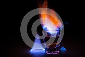 Closeup shot of flaming vodka in glass on dark background