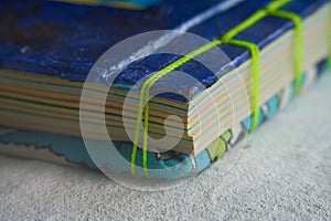 Closeup shot of folded paper sheets bound with green thread