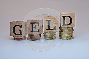 Closeup shot of four group of coins with four cubes on them has letters GELD on isolated background