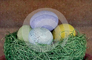 Closeup shot four pastel colored eggs in a green nest