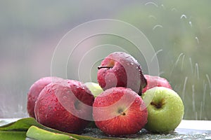 Closeup shot of fresh apples in the rain on a banana leaf