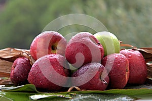 Closeup shot of fresh apples in the rain on a banana leaf