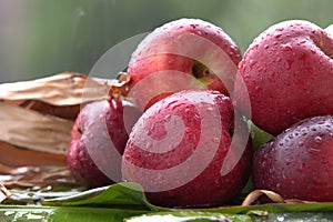 Closeup shot of fresh apples in the rain on a banana leaf