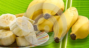 Closeup shot of fresh bananas on a leaf and cut banana pieces on a plate