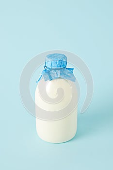 closeup shot of fresh milk in bottle wrapped by paper on blue background