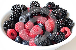 Closeup shot of fresh mixed berries on a bowl isolated on a white background