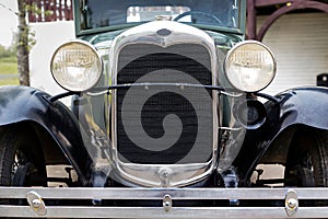 Closeup shot of the front part of an old car with round headlights
