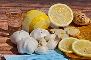 Closeup shot of garlic, lemon, ginger, a drink, and sanitary mask - concept of folk remedies